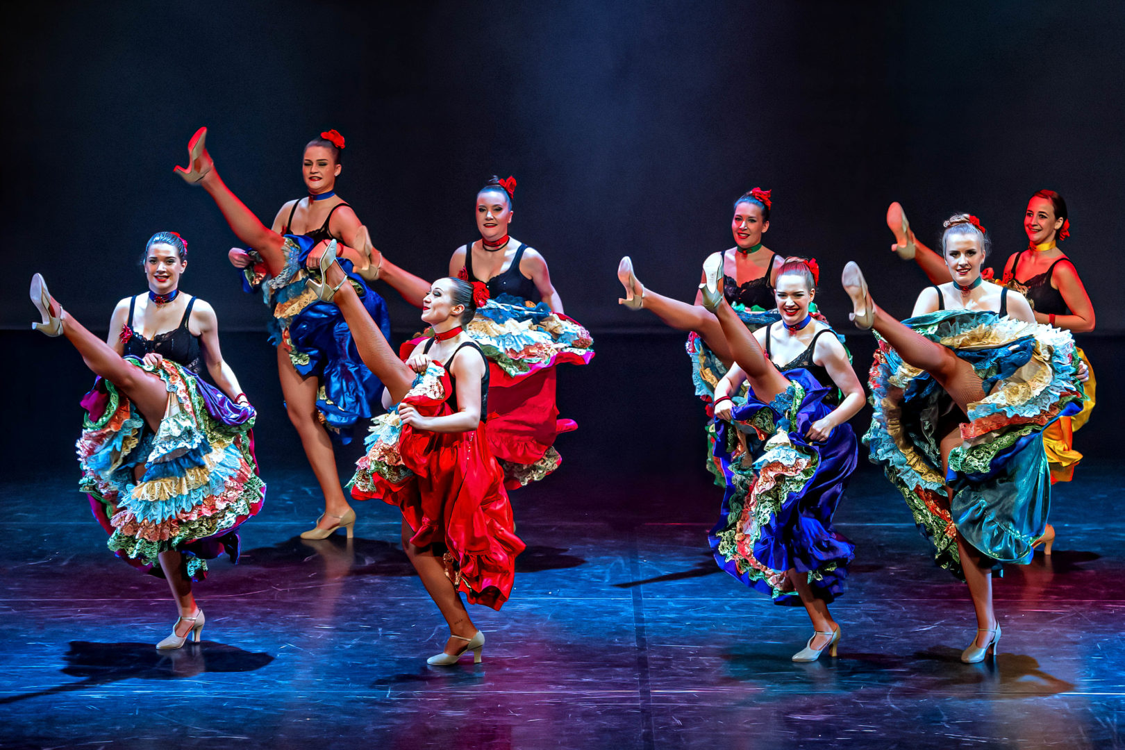 Dansers in kleurrijke kostuums tijdens een groepschoreografie op het podium